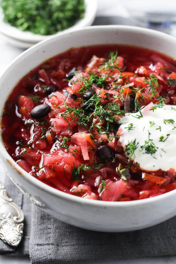 Borscht in a bowl garnished with sour cream and dill.