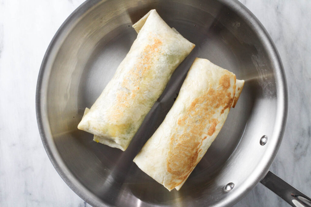 Two tortilla wraps on a skillet.