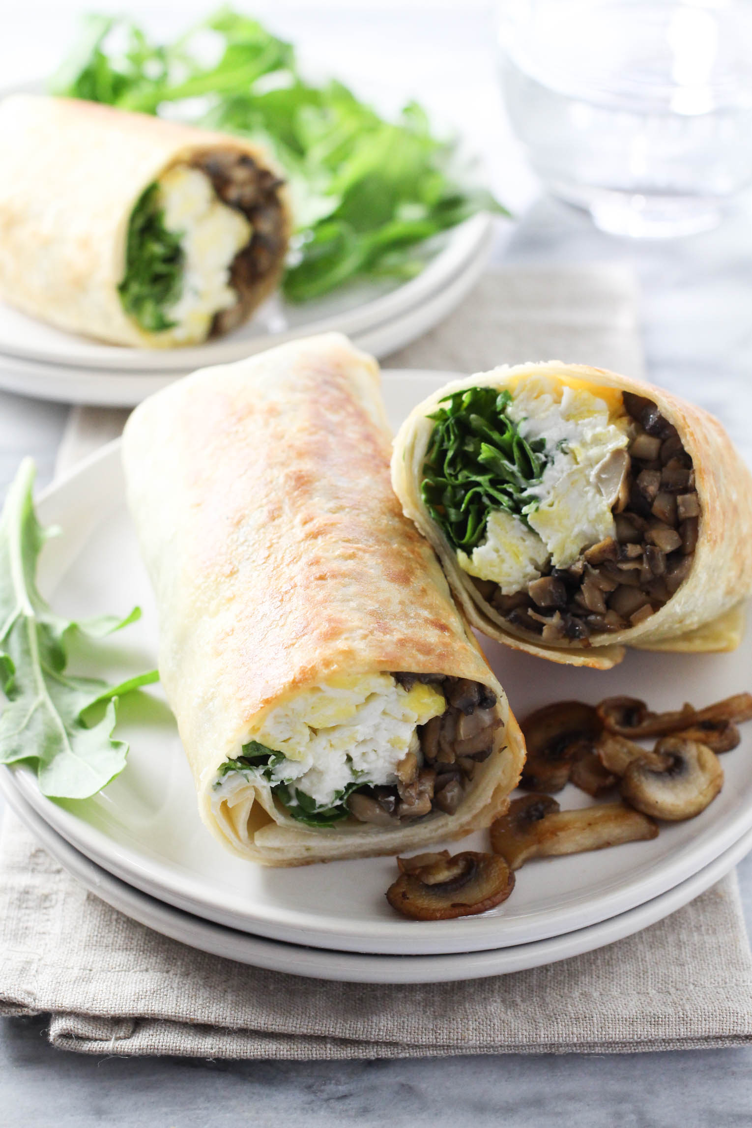 Sliced mushroom wrap on a plate. Arugula in the background.