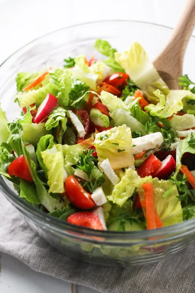 Romaine salad with chopped veggies and feta in a glass bowl.
