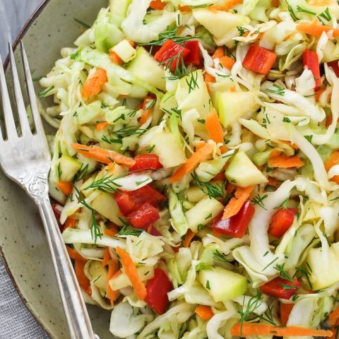 Healthy cabbage salad on a plate with a silver fork on the right side.