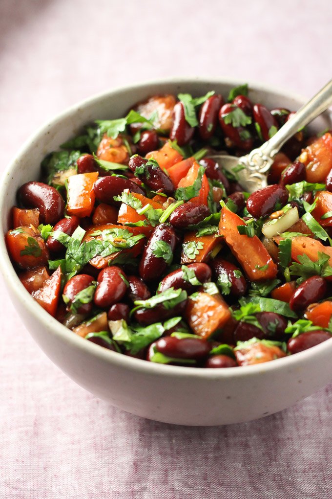Red bean salad with tomatoes and fresh herbs in a bowl.