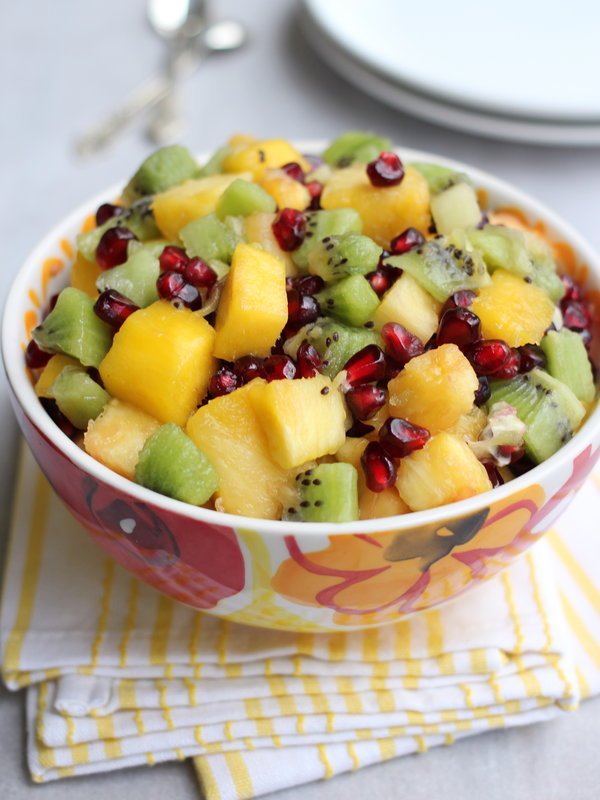 Fruit salad in a multicolored bowl standing on a tea towel.