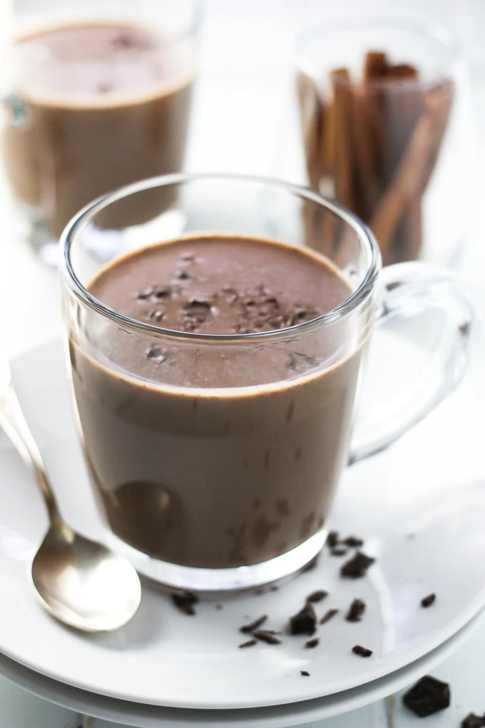 Healthy cinnamon hot chocolate in a glass mug. Cinnamon sticks in the background.
