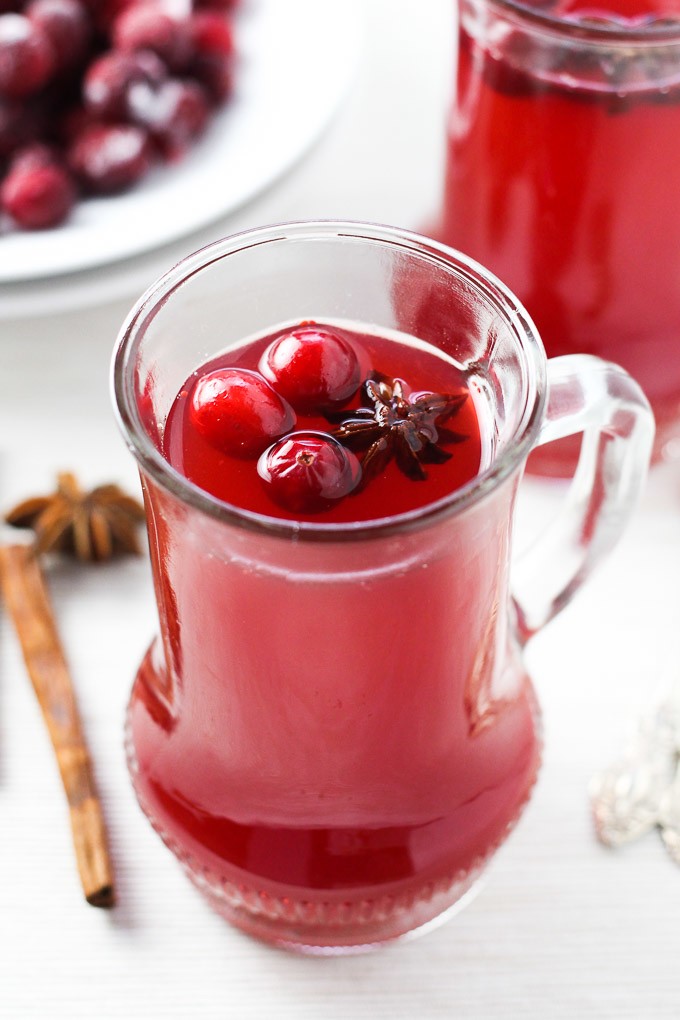 Christmas punch in a glass jug garnished with fresh cranberries and star anise.
