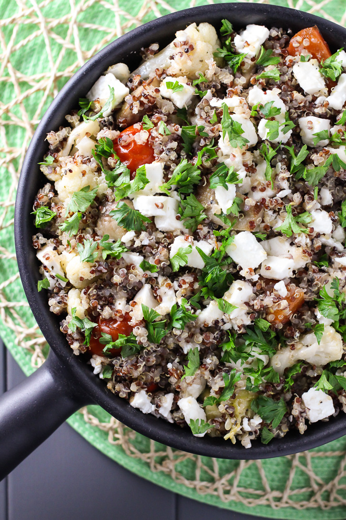 Overhead shot of quinoa bake with feta in a black pan. The dish is garnished with parsley.