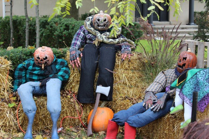 Three large halloween figures sitting on straw.