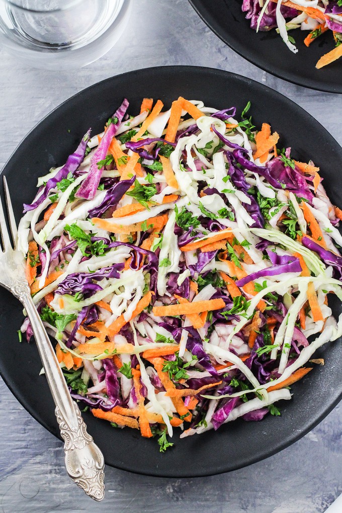 Overhead shot of the red and green cabbage salad on a black plate. Silver spoon to the left.