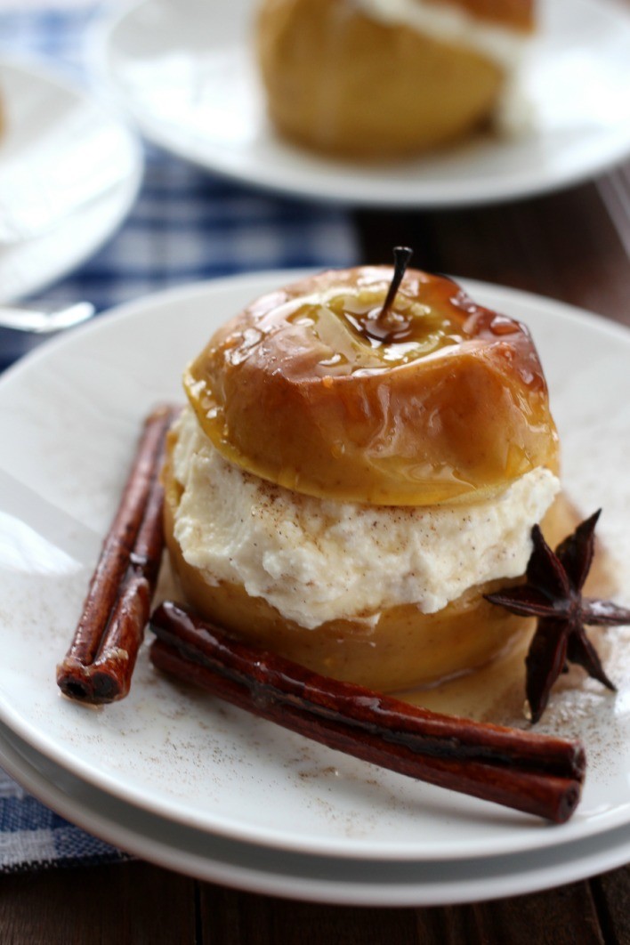Baked apple with ricotta on a white plate, garnished with cinnamon and anise.