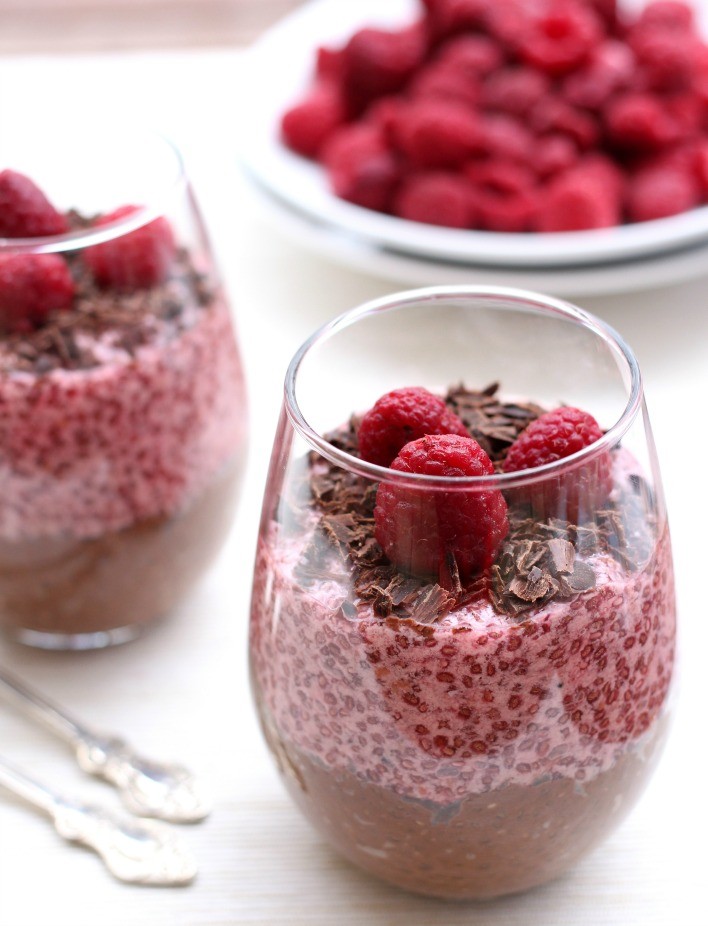Chocolate and raspberry chia pudding in a glass. Fresh raspberries in the background.