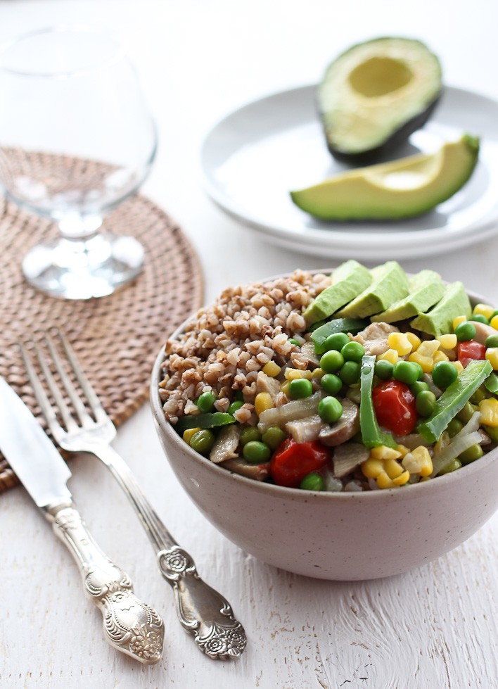 Chicken stew in a bowl. Garnished with avocado slices. Silver fork and knife to the left.