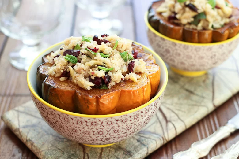 Roasted acorn squash seeds stuffed with quinoa salad, served in bowls.