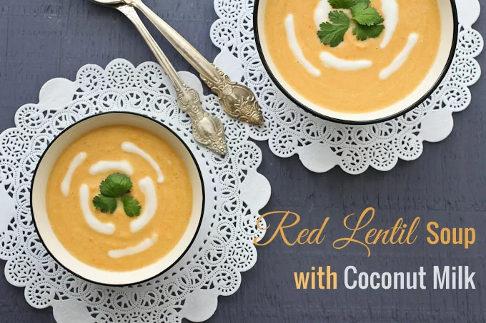 Overhead shot of two bowls with soup standing on napkins. Silver spoons in the middle and a text overlay saying: red lentil soup with coconut milk.
