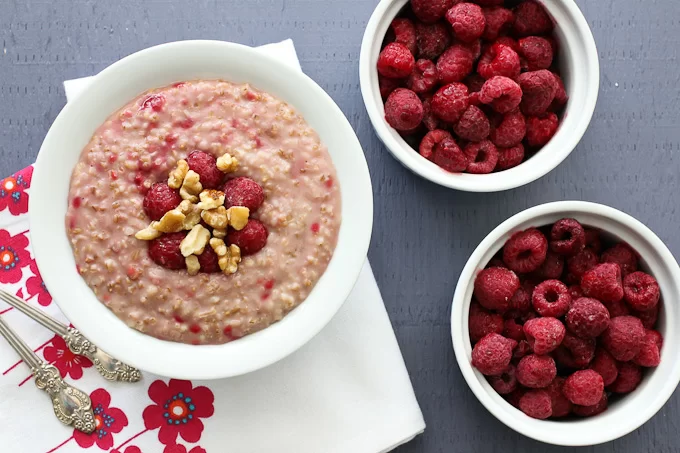 Raspberry steel-cut oats in a bowl and two bowls with raspberries.