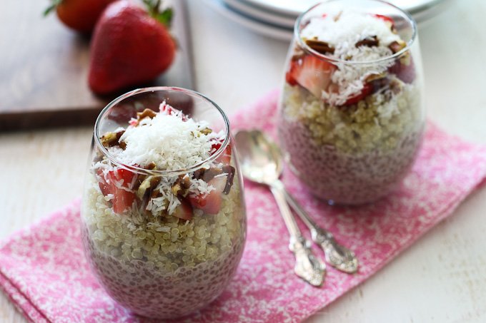 Two glasses with strawberry chia layered with quinoa and garnished with shredded coconut.