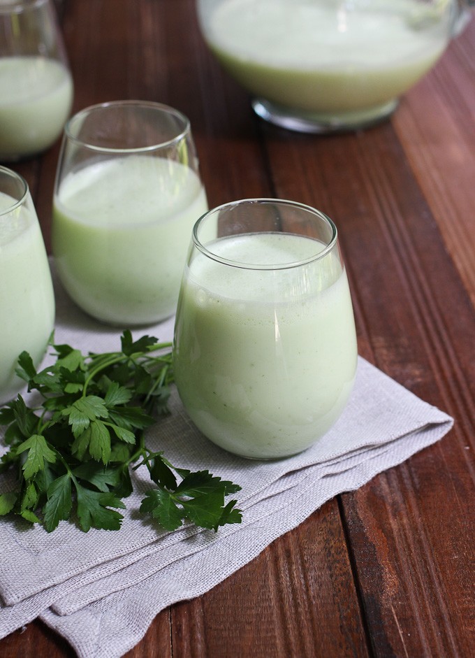 Armenian yogurt drink in glasses standing on a napkin. Fresh parsley to the left.