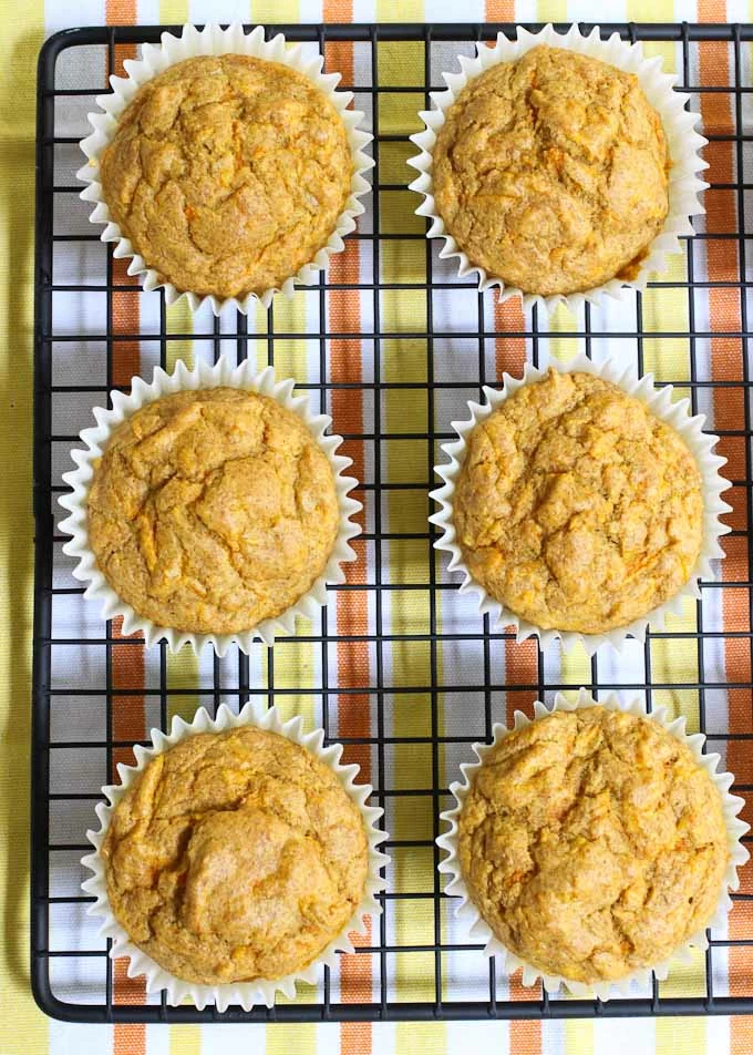 Overhead shot of six savory carrot muffins on a cooling rack.