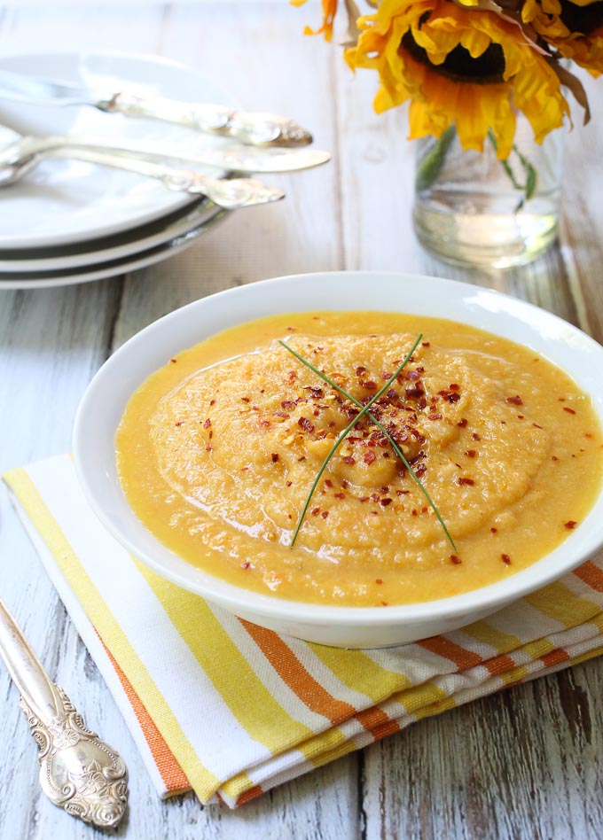 A bowl of the creamy cauliflower and carrot soup seasoned with red pepper flakes.