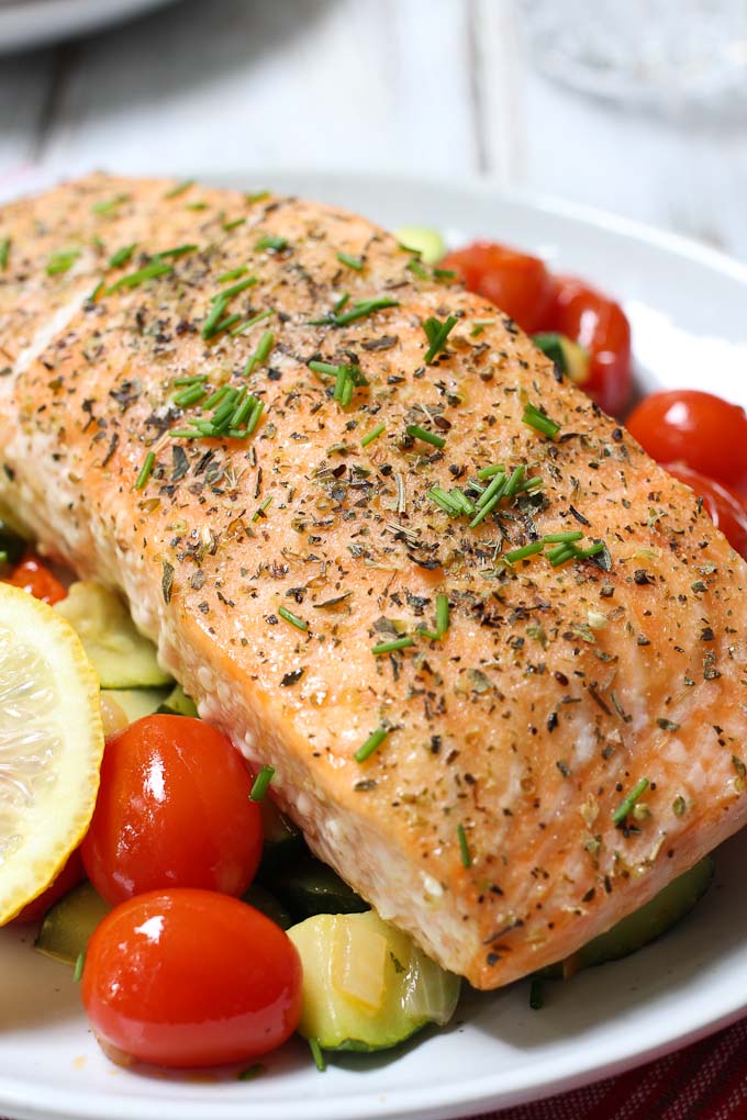 Roasted salmon with veggies on a white plate.