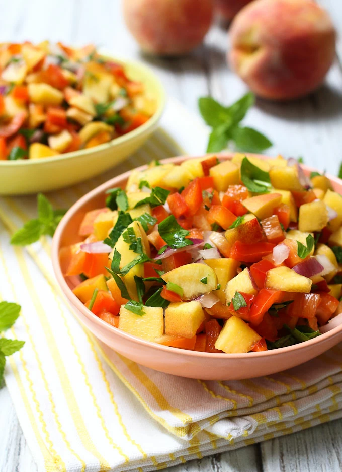 Peach salsa in a bowl standing on a kitchen towel.