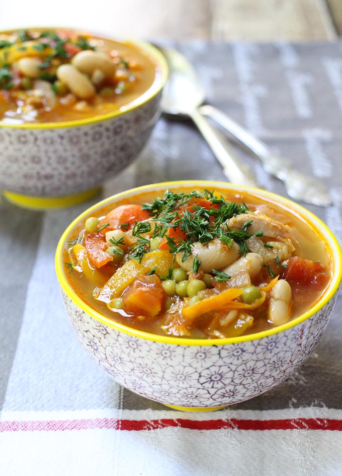 Chicken and white bean soup in bowls standing on a tea towel.