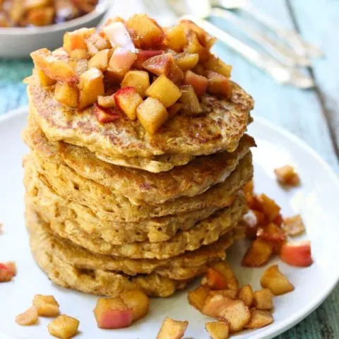 Healthy oatmeal pancakes with the apple topping on a white plate.
