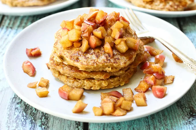 Oatmeal pancakes with apple topping. Served on a white plate.
