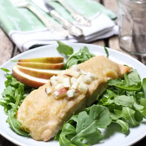 Roasted salmon with apple sauce on a plate with arugula salad.