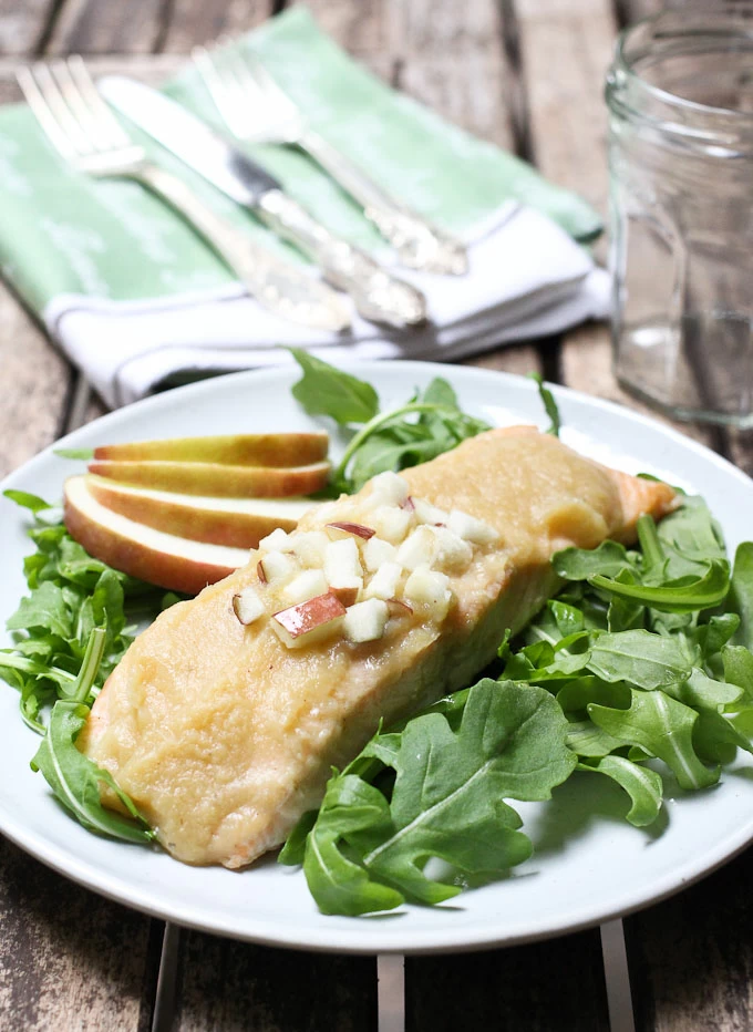 Roasted salmon with apple sauce on a plate with arugula salad.