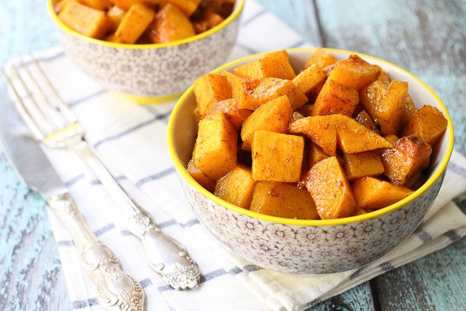 Roasted butternut squash cubes with maple syrup in a bowl.