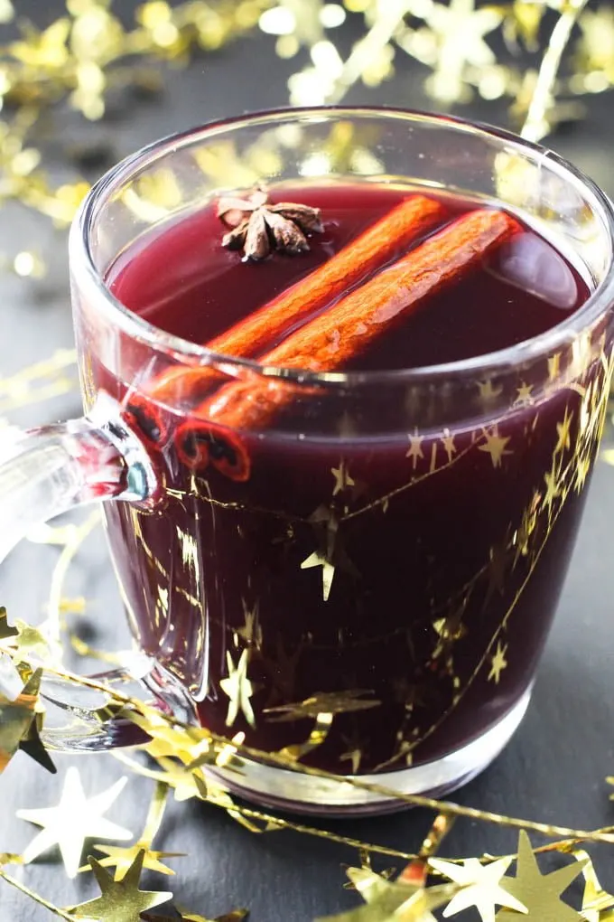 Close up of red Gluhwein in a mug decorated with cinnamon sticks and star anise.