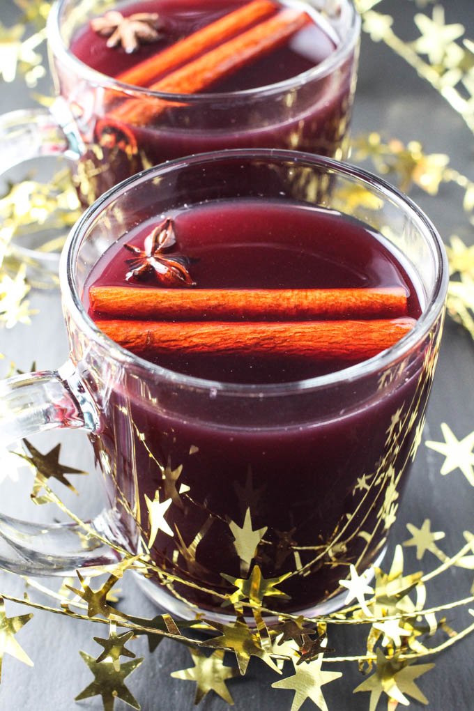 Red Gluhwein in mugs garnished with anise stars and cinnamon sticks.