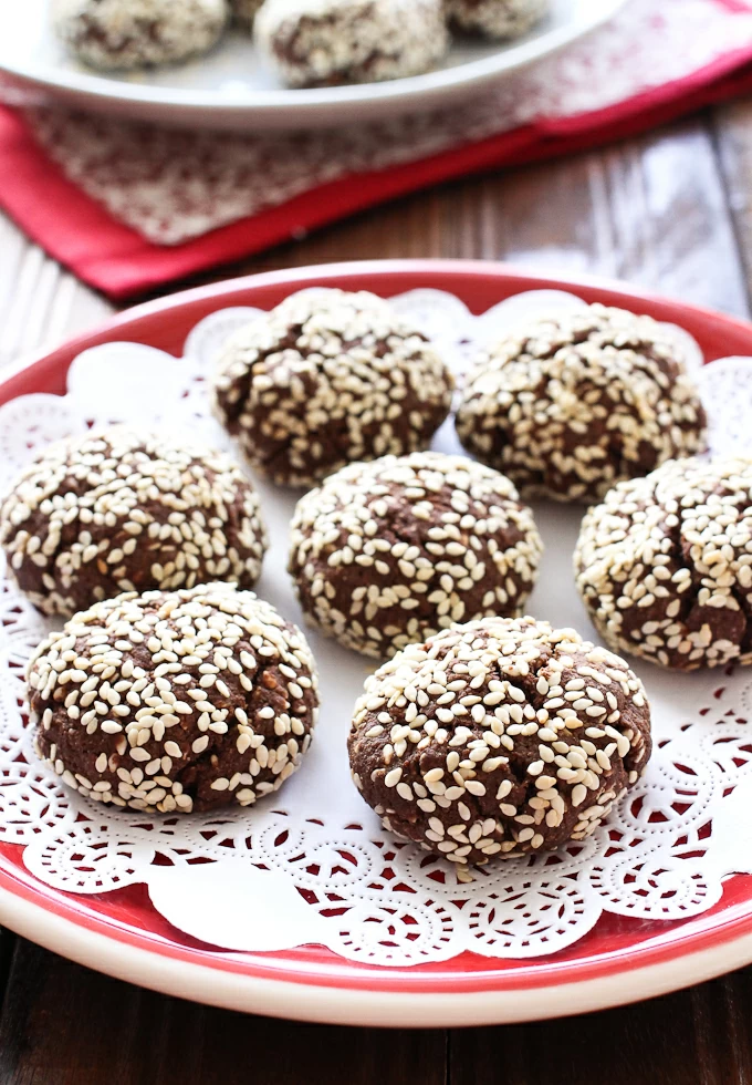 Chocolate cookies with sesame seeds on a red plate.