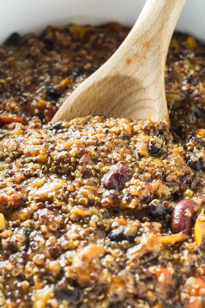 Quinoa chili being mixed with a wooden spoon.