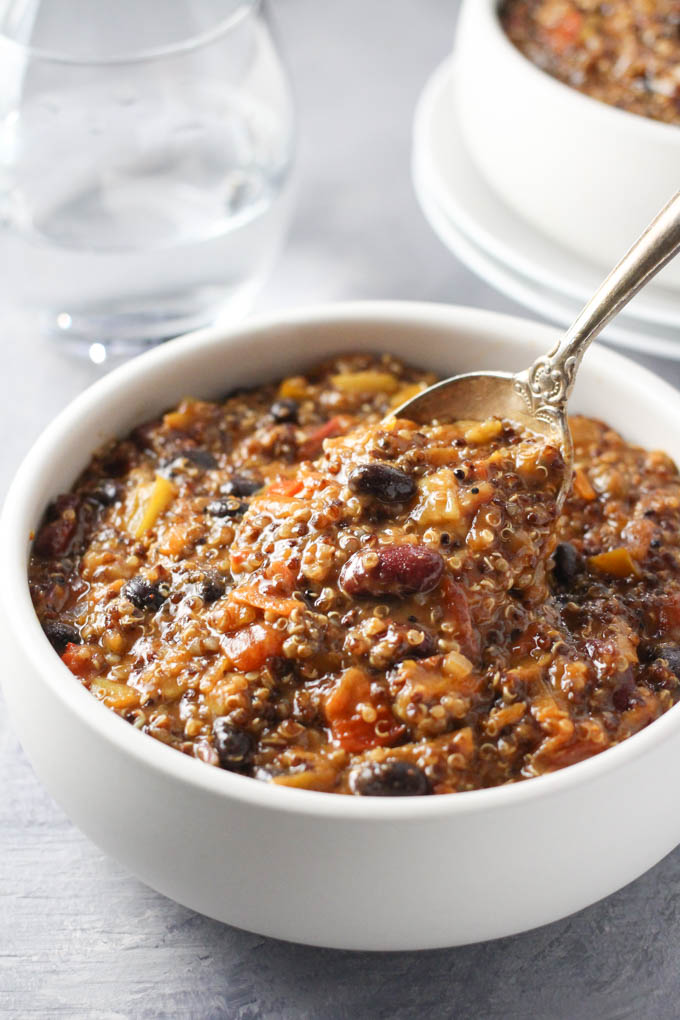 Quinoa chili being scooped with a spoon out of a bowl.