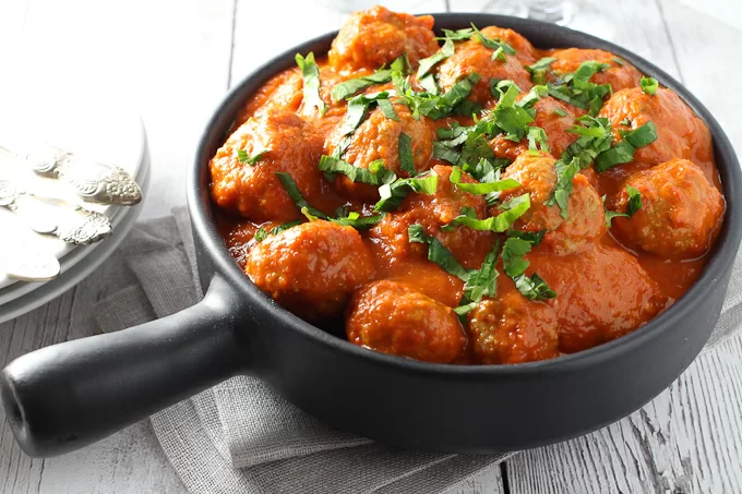 Meatballs in Red Pepper Sauce in a skillet.