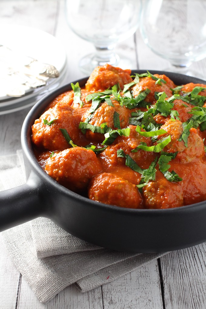 Healthy turkey meatballs in black skillet. Garnished with parsley.