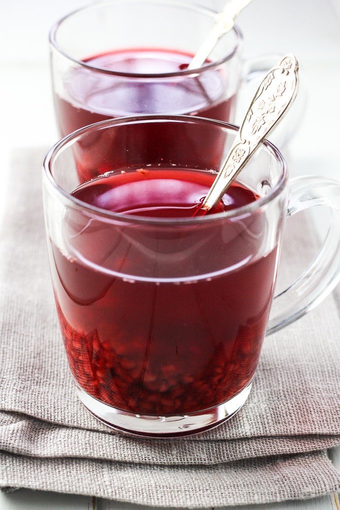 Jasmine raspberry tea in a glass cup with a silver spoon in it.