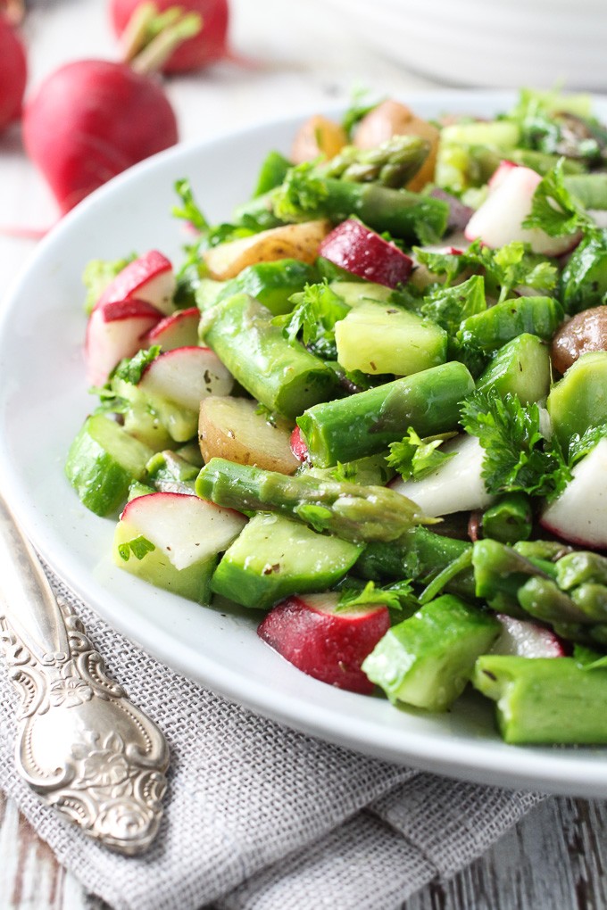 Potato salad with asparagus on a white plate.