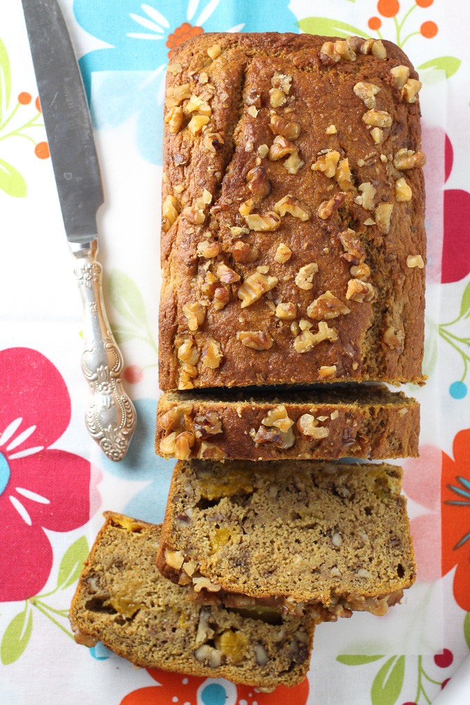 Top view of the partially sliced healthy mango bread loaf with a silver knife on the left.