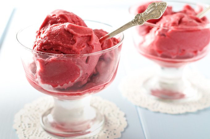 Vegan raspberry ice cream in a glass with a silver spoon.