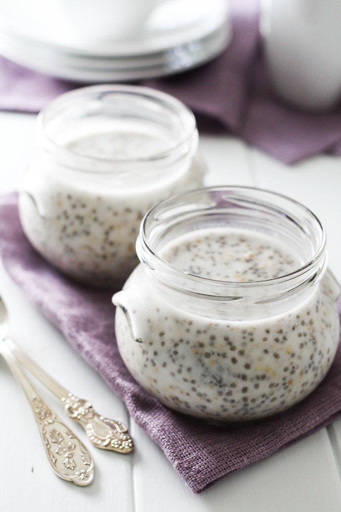 Overnight steel cut oats in two jars standing on a tea towel. Two silver spoons in front of the jars.