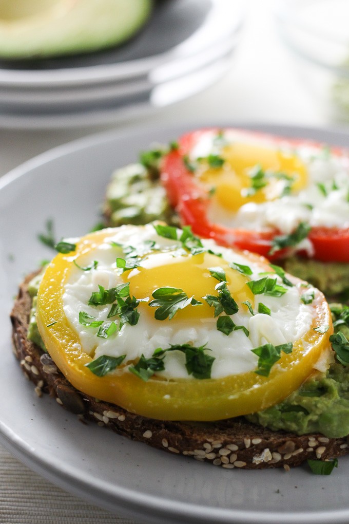 Close-up side view of a Egg Avocado Toast on a white plate garnished with parsley.