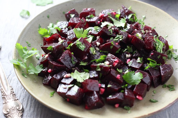 A close-up side view of the Mediterranean Beets with Garlic and Olive Oil on a plate with a silver fork on the left.