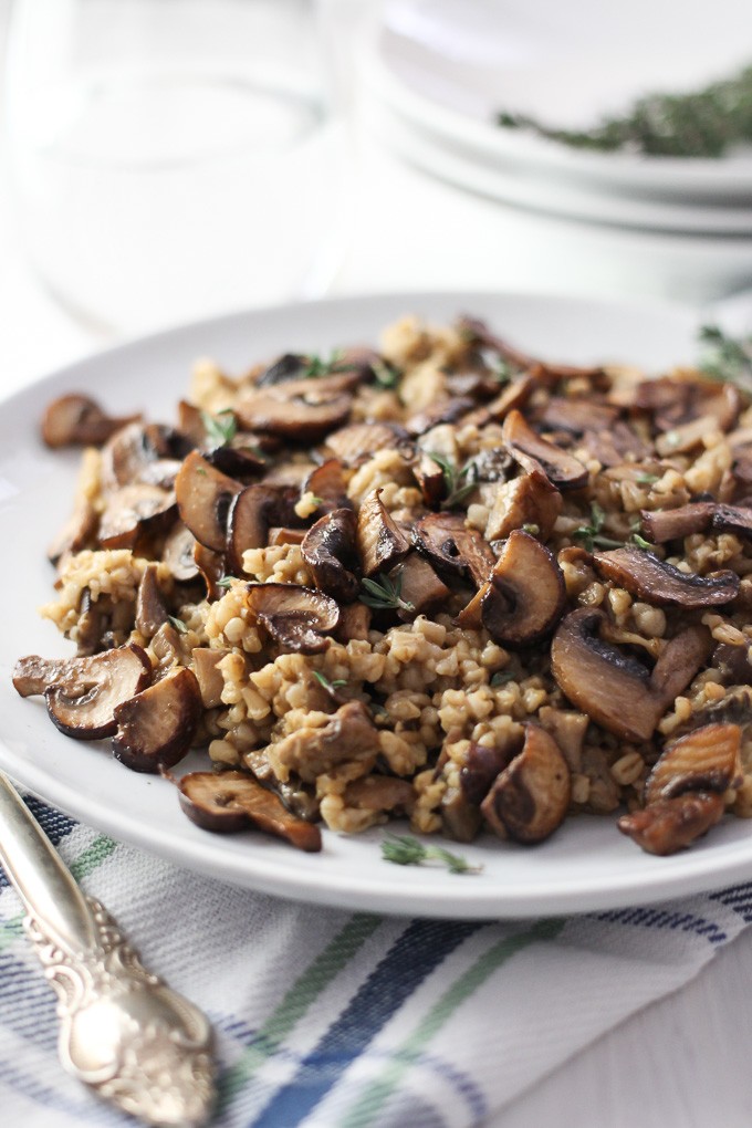 Close-up side view of the Savory Steel Cut Oats with Mushrooms and Thyme on a white plate placed on a kitchen towel.