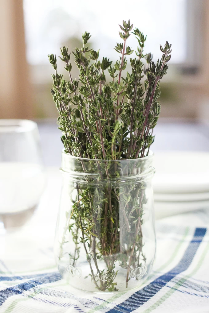 Close-up side view of a bunch of thyme in a jar standing on a kitchen towel.