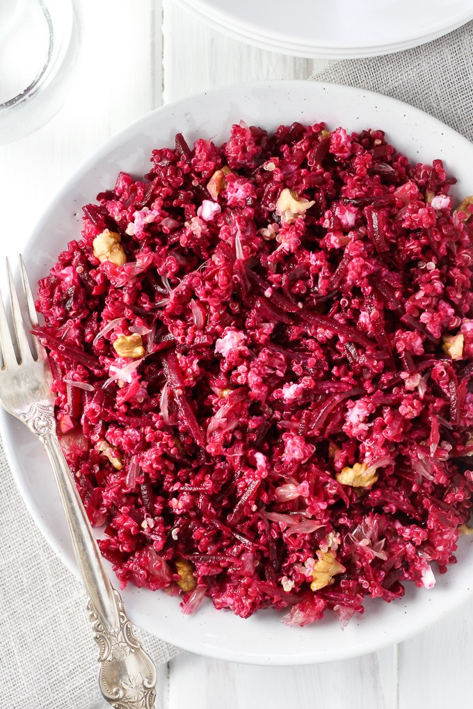 Beet Quinoa Salad with Goat Cheese and Grapefruit on white plate with silver spoon on the left.