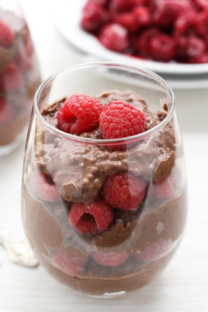 Chocolate chia pudding with whole raspberries in a glass.