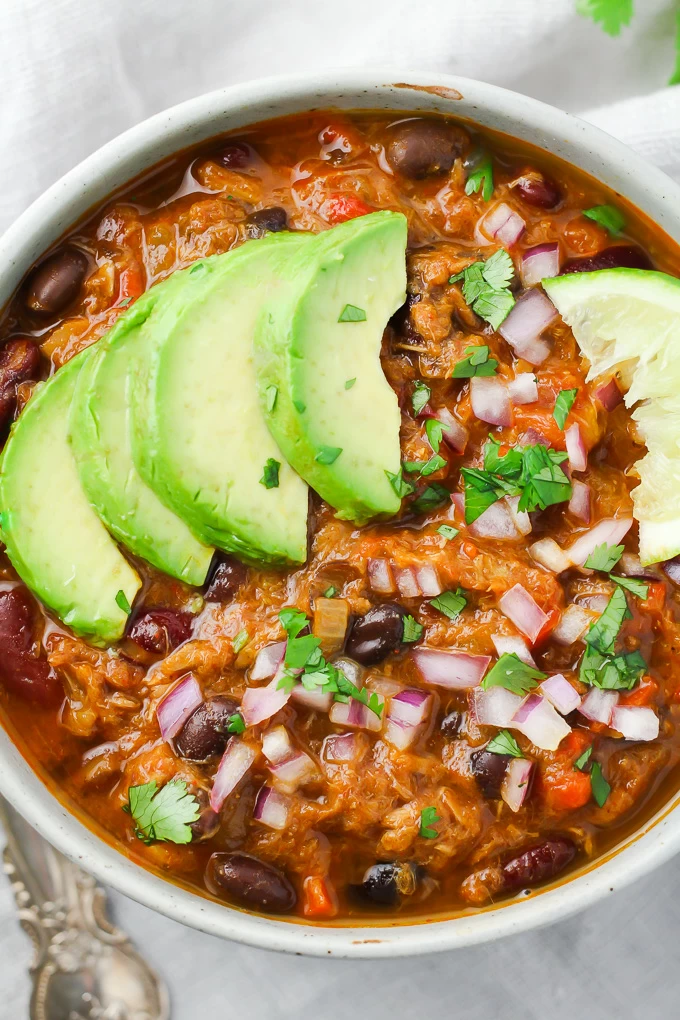 Tuna chili in a bowl garnished with avocado and red onion.