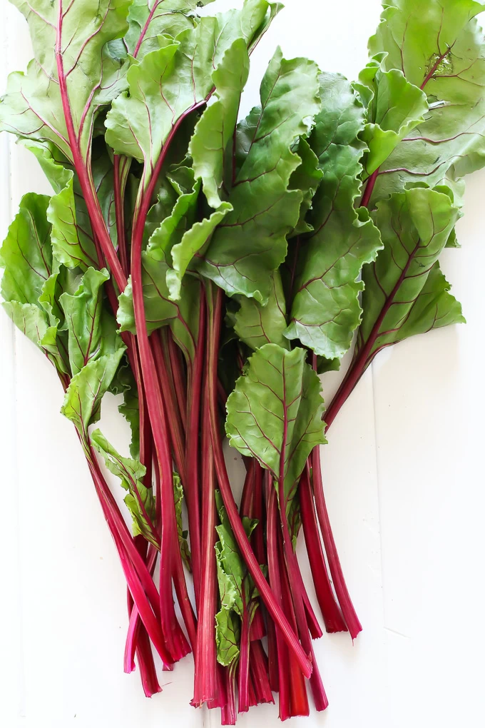 A bunch of beet greens on a white background.